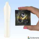 A hand with pink-painted nails holds a black and gold condom wrapper labeled "ID Extra Large Premium Condoms" from ID Condoms. Next to it on the left is an unwrapped, white, elongated condom. The background transitions from light blue to white, showcasing the Condomania logo at the bottom right. Ideal for those seeking premium lubricated latex condoms.